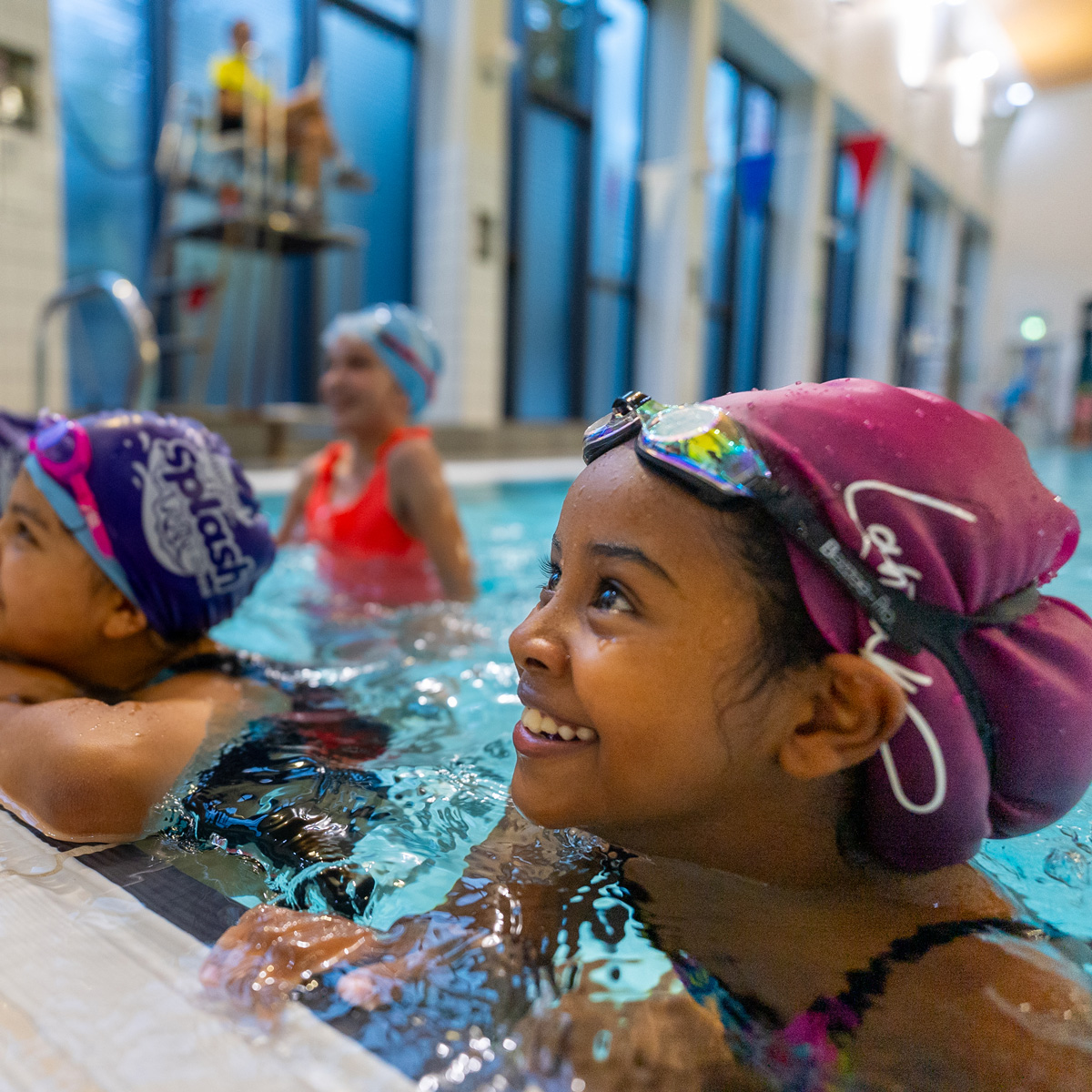 Girl in swimming pool smiling in the direction of the swim teacher